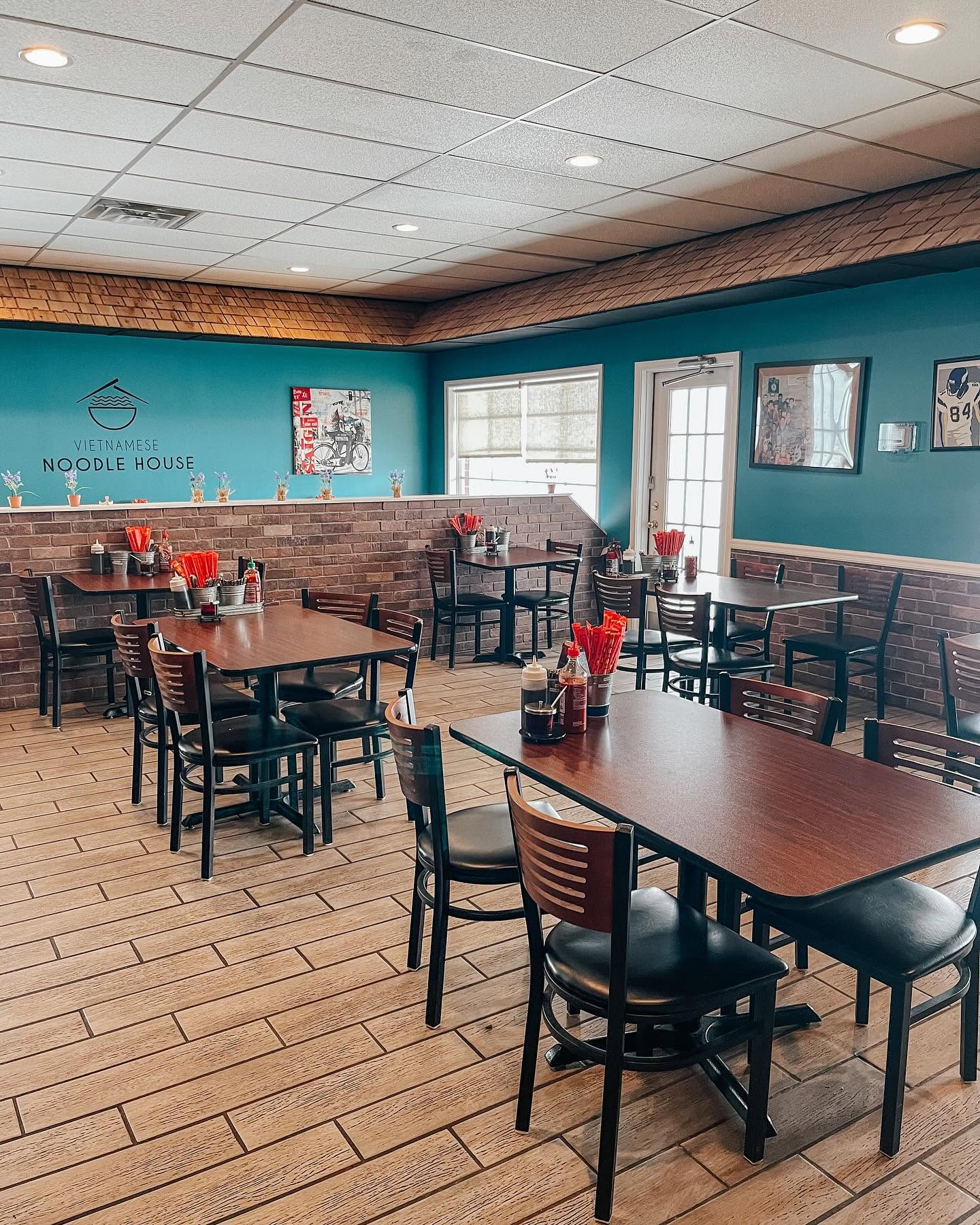 Dining room seating beneath the Vietnamese Noodle House logo wall